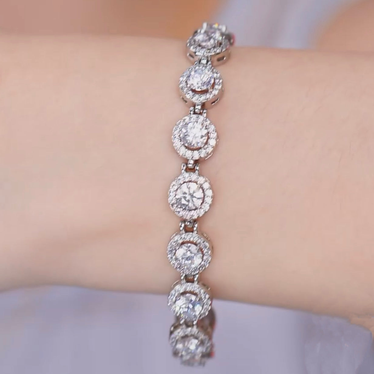 Close-up of a silver bracelet with round diamonds on a light-skinned wrist.